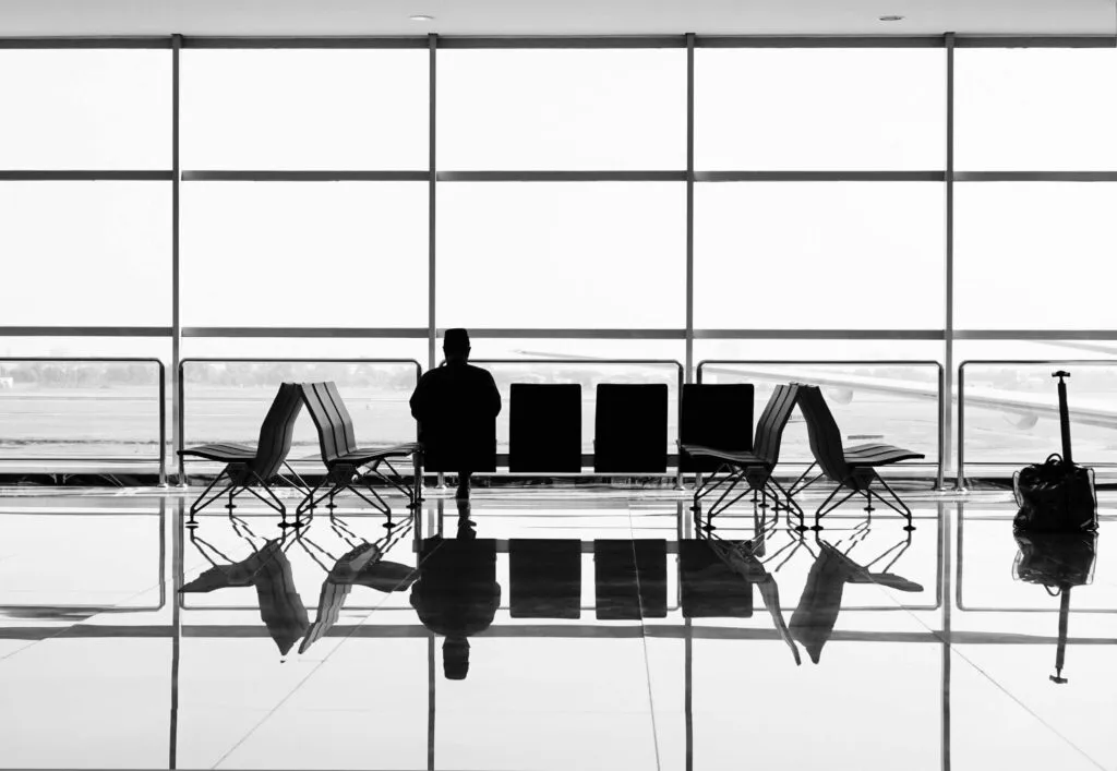 Traveller sitting and looking out an airport window. Photo by Suganth on Unsplash