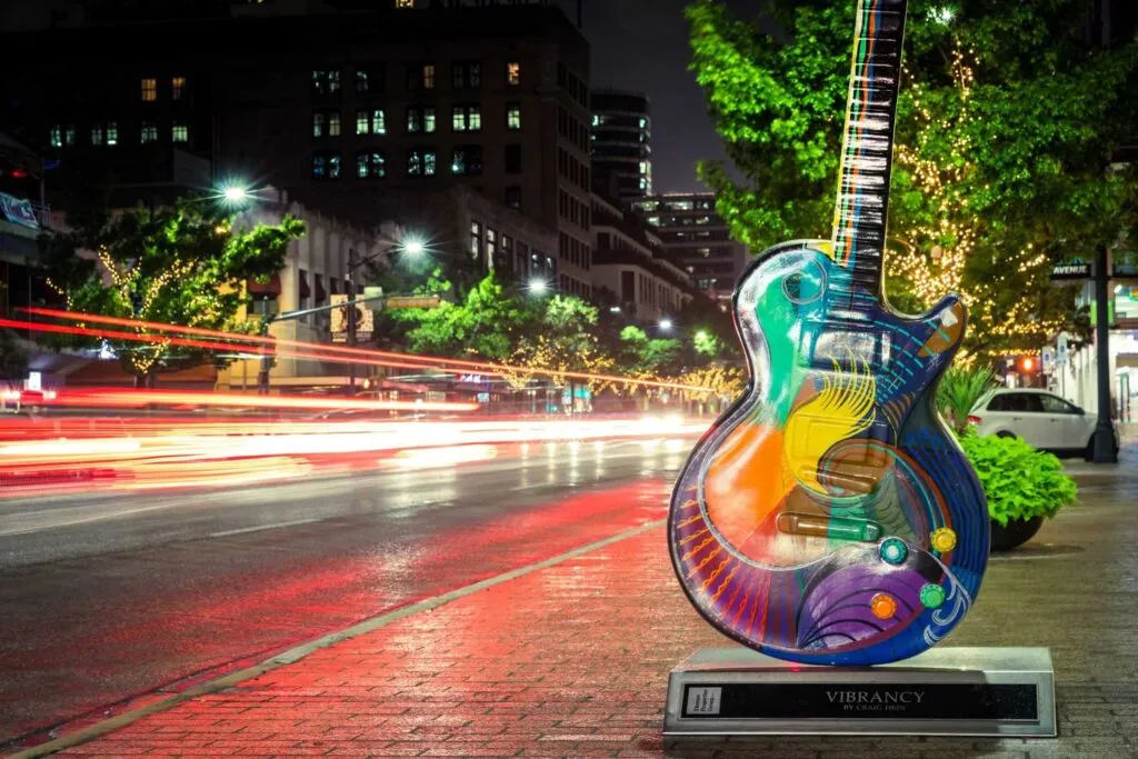 Lit-up guitar sign on busy road in Austin