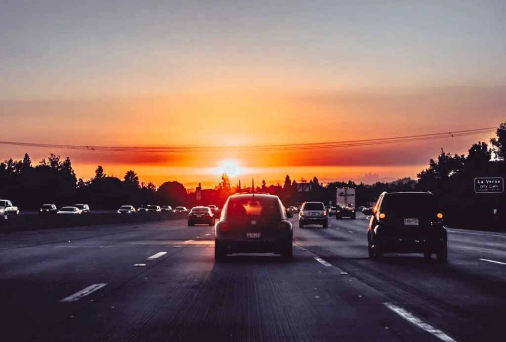 Cars driving into sunset. Photo by Xan Griffin on Unsplash