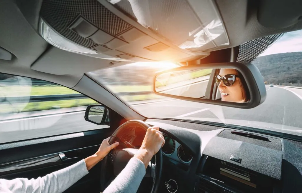 Woman drive a car reflects in back view mirror