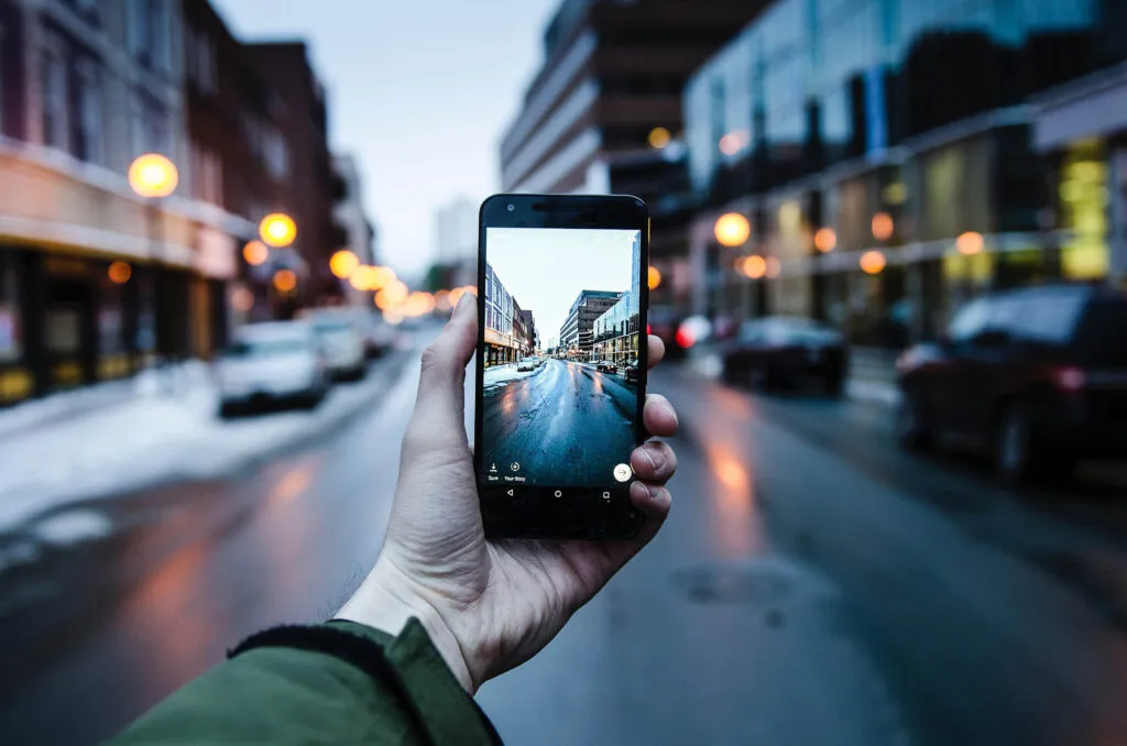 Man holding a phone, with a view of a street through the phone