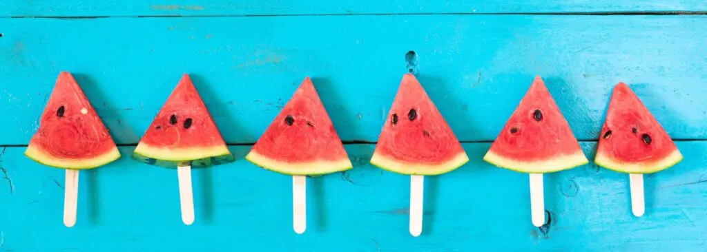 summer watermelon slice popsicles on a blue rustic wood background