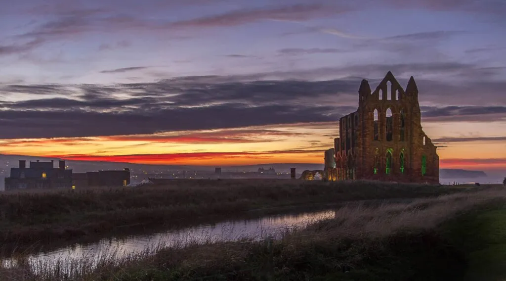 Illuminted image of the ruined Whitby Abbey against a sunset sky